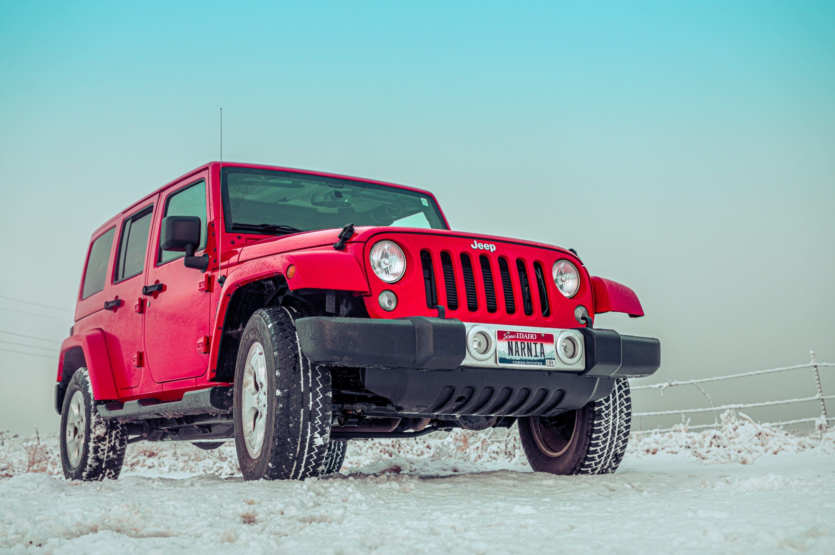 A red jeep is parked in the snow.